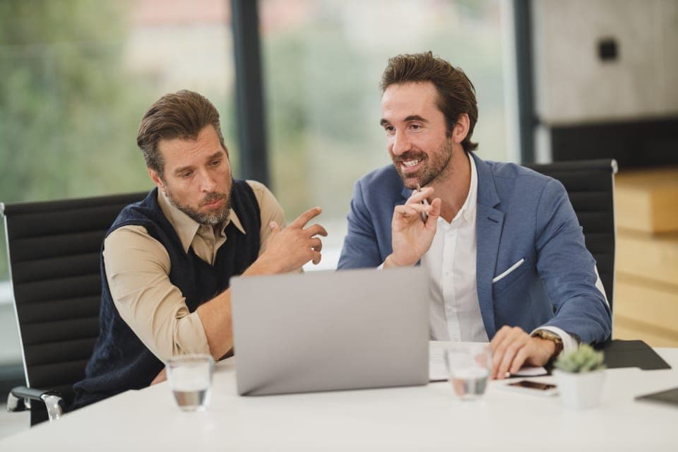 Two colleagues talking over a laptop in a meeting